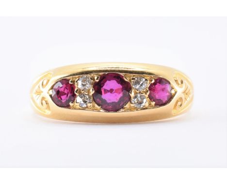 An 18ct gold ruby and diamond ring set with three round cut graduating rubies with four round cut diamonds set in between. Ma