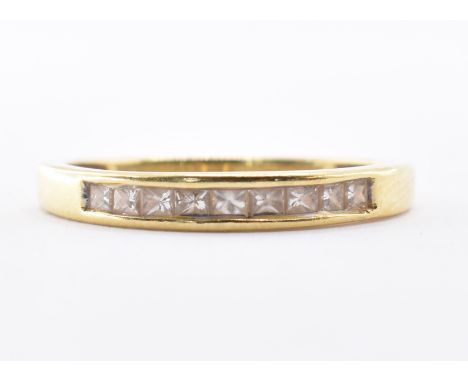 An 18ct gold band ring being channel set with nine square cut diamonds. Marked 18K. Weight 1.9g. Size N.