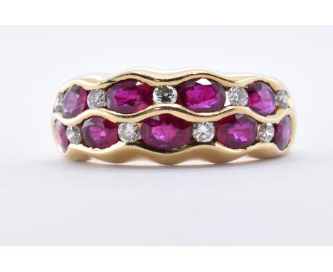 &nbsp;A hallmarked 18ct gold and ruby and diamond band ring. The ring having 9 oval mixed cut rubies and 9 round brilliant cu