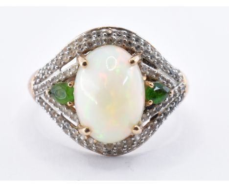 A stamped 9ct gold TJC ladies dress ring having a central opal cabochon flanked by two pear cut green stones and surrounded b