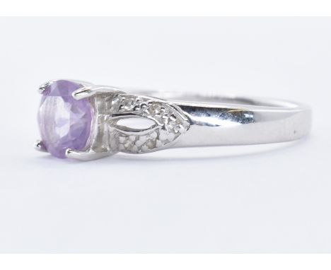 A hallmarked 9ct white gold ring having a central amethyst stone within a claw setting and illusion set diamonds to the pierc