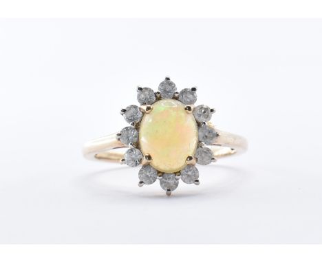 A hallmarked 9ct gold ring being set with a central opal cabochon with a halo of round cut white stones. Assay marked for Lon