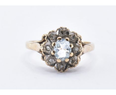 A hallmarked 9ct gold ring having a central white oval cut stone and eight foil set white stones surrounding. Hallmarked for 