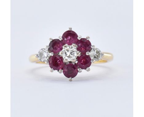 A hallmarked 18ct gold diamond and ruby cluster ring having a central brilliant cut diamond surrounded by six round cut rubie