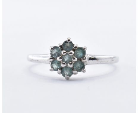 A 9ct hallmarked white gold and green stone cluster ring set with seven round cut stones in a flower head. Hallmarked Birming