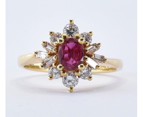 A hallmarked 18ct gold ruby and diamond cluster ring being set with a central oval cut ruby having a halo of round and baguet