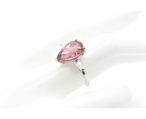 A white gold ring set with a central pear cut pink tourmaline flanked by two tapering diamonds to the shoulders. Band unmarke