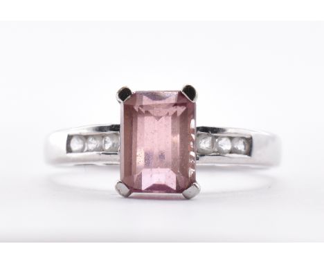 A hallmarked white gold ring being set with a rectangular pink stone having six channel set white accent stones to the should