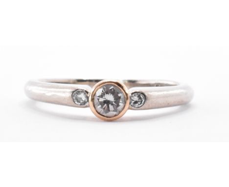 An 18ct gold and diamond three stone ring having a central bezel set round cut diamond with two further round cut diamonds to