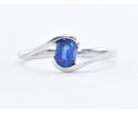 A hallmarked 9ct white gold crossover ring being set with an oval cut sapphire. Hallmarked Birmingham 2006. Weight 2.0g. Size