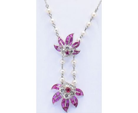 A vintage platinum diamond and ruby pendant having two floral sprays each having a flower set with five round cut diamonds an