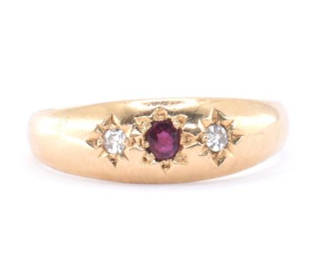 An 18ct gold ruby and diamond gypsy ring. The ring set with a central round mixed cut ruby flanked by two old cut diamonds wi