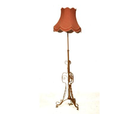 Early 20th Century gilt metal adjustable standard lamp of open scroll design on tripod support, with shade   Condition: 