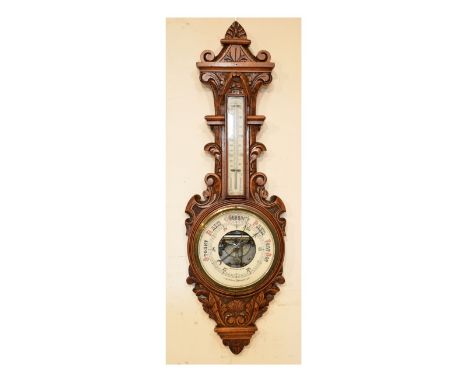 Early 20th Century carved oak cased aneroid barometer and thermometer, the white ceramic dial with a visible mechanism to the
