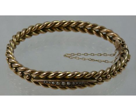 A Victorian 9ct rose gold and pearl bangle, stamped 9ct, the front with a row of half pearls, to woven pattern body, weight 1