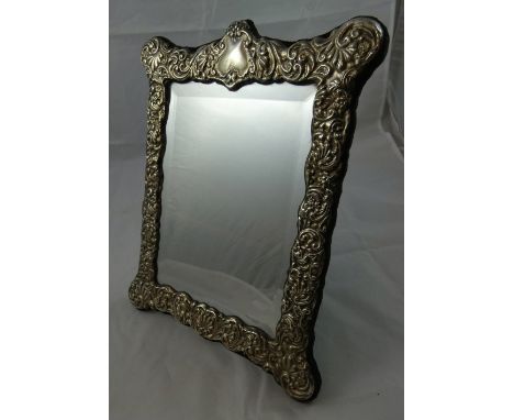 A silver easel mirror, Birmingham 1991, the bevel glass bordered by an embossed scroll border, 30 x 23 cm.