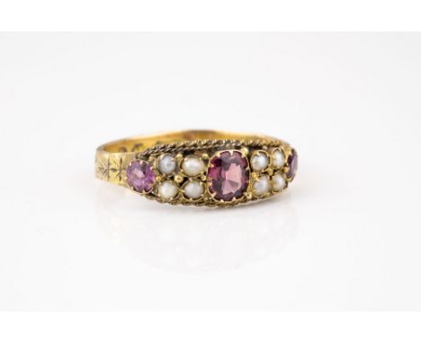 A Victorian 15ct gold, ruby and seed pearl ring, hallmarked Birm. 1870, the central oval cut and smaller round cut rubies div