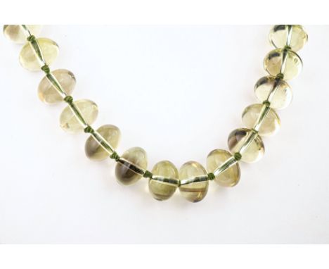 An unusual vintage polished citrine bead necklace, with evenly sized ovoid beads of pale, yellow-green citrine, with 9ct gold