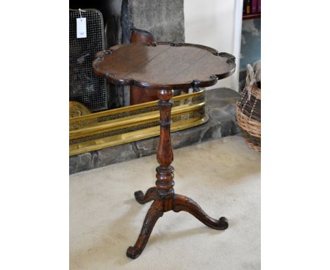 A William IV oak tripod table, the scalloped circular top with carved scroll border, on a lappet carved and turned baluster c