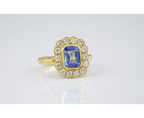 An Edwardian style 18ct yellow gold, sapphire and diamond cluster ring, the 1.81ct emerald cut, cornflower blue sapphire with