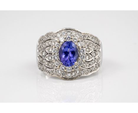 An 18ct white gold, Tanzanite and diamond ring, the oval cut Tanzanite within a border of brilliant cut diamonds, over a deco