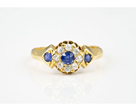 An 18ct yellow gold, sapphire and diamond cluster ring, the central round cut sapphire within a border of eight old brilliant