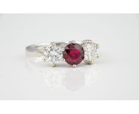 An 18ct white gold, ruby and diamond three stone ring, the central round cut 1.18ct unheated ruby flanked by a pair of brilli