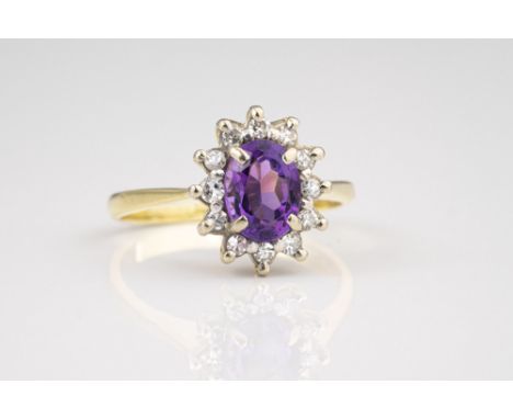 An 18ct yellow gold, amethyst and diamond cluster ring, the oval cut 8 x 6mm. amethyst within a border of twelve eight cut di