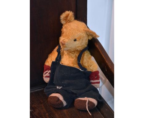 A much loved vintage golden mohair teddy bear, 1930s, wearing corduroy dungarees.