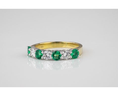 An 18ct yellow and white gold, emerald and diamond half eternity ring, the four round cut emeralds, total 0.57ct, divided by 