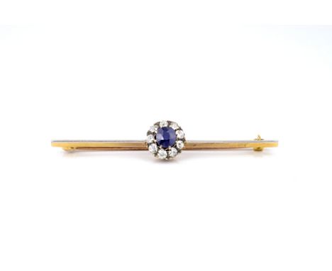 An antique 15ct yellow gold, platinum, faux sapphire and diamond cluster bar brooch, the central oval cut sapphire within a b