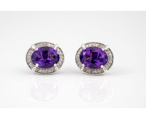 A pair of 9ct white gold, amethyst and diamond cluster stud earrings, the oval cut amethysts within a border of eight cut dia