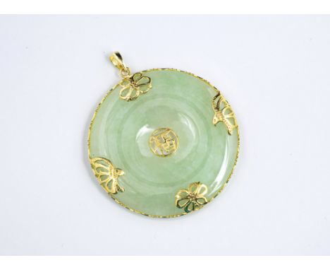 A 14ct yellow gold mounted jade bi-disc pendant, the mottled celadon jade disc within a pierced 14ct gold frame, 38mm. diamet