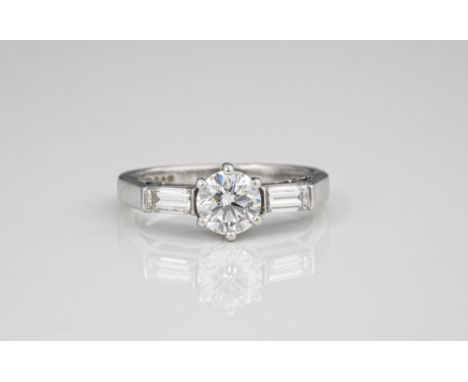 A platinum and diamond three stone ring, the centre 0.75ct brilliant cut diamond flanked by a pair of baguette cut diamonds, 