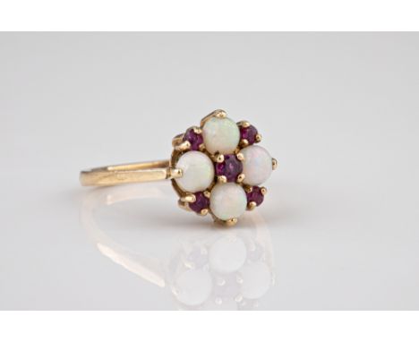 An Edwardian 9ct gold white opal and ruby ring, the four white opals in a Tudor rose pattern interspersed and centred by circ