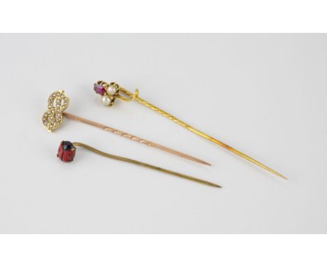 Two antique gold stick pins, one in 18ct gold, the entwined scrolls set with seed pearls, on a 9ct rose gold pin, the other 1