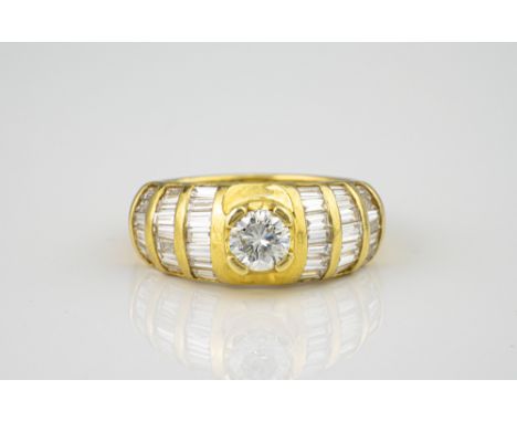 A French 18ct yellow gold and diamond ring, the central brilliant cut diamond flanked by shoulders set with bands of baguette