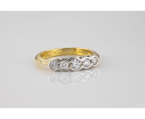 An 18ct yellow and white gold diamond five stone ring, the five graduated brilliant cut diamonds in rub over settings, total 