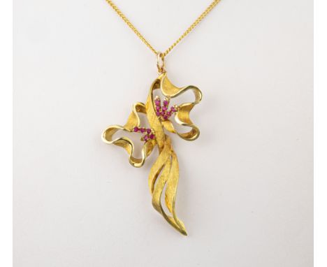 A vintage 18ct yellow gold and ruby pendant, the brushed gold, tied ribbon pendant set with small round cut rubies, 6cm. long