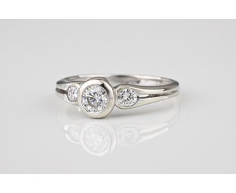 An 18ct white gold and diamond three stone ring, the central brilliant cut diamond over pierced shoulders set with two smalle