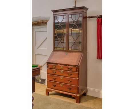 A George III mahogany bureau bookcase, of small proportions, the flared cornice over two 13 pane astragal glazed doors enclos