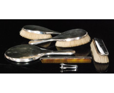 A George V hallmarked silver backed dressing table set composed of three brushes, a hand mirror and a comb, each with engine 