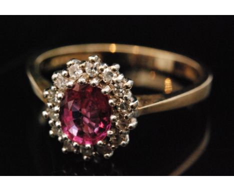 A 9ct hallmarked ruby and diamond cluster ring, central oval ruby within a fourteen stone diamond surround, all stones claw s