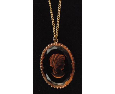 An oval faceted smokey quartz pendant intaglio depicting a maiden's head in profile, claw set to a pierced mount with yellow 