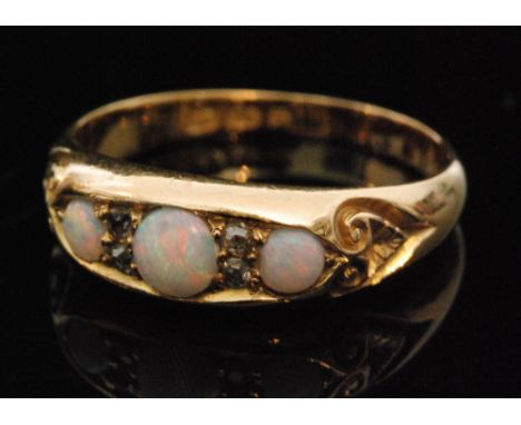 A hallmarked 18ct opal and diamond boat head ring, set with three graduated round opals and spaced by two pairs of diamonds t