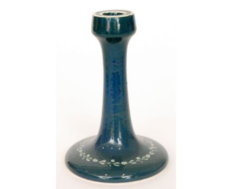 A Ruskin Pottery souffle glazed candlestick decorated to the foot with a hand painted garland of flowers, the whole in a blue