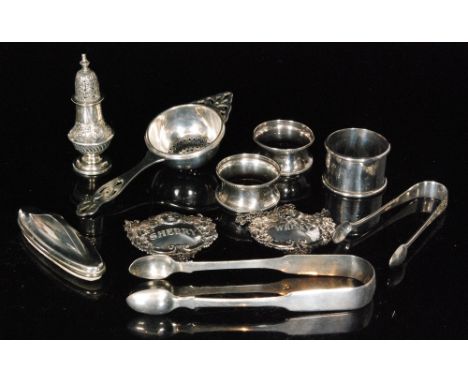 Ten assorted silver items to include three napkin rings, a tea strainer, two decanter labels, sugar tongs etc, various styles