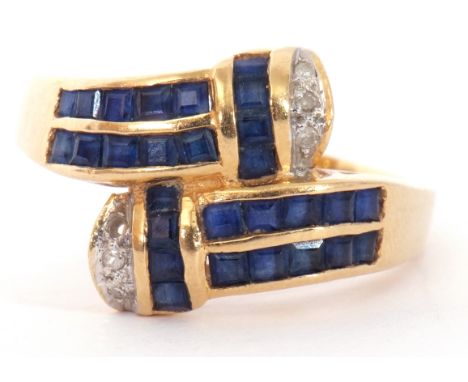 Modern sapphire and diamond cross over ring, each shoulder with 14 small calibre cut sapphires, pave set with ends decorated 