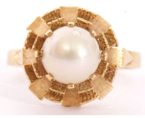 Modern yellow metal and cultured pearl ring centring a cultured pearl, 6mm diam, multi-claw set and raised in a textured moun