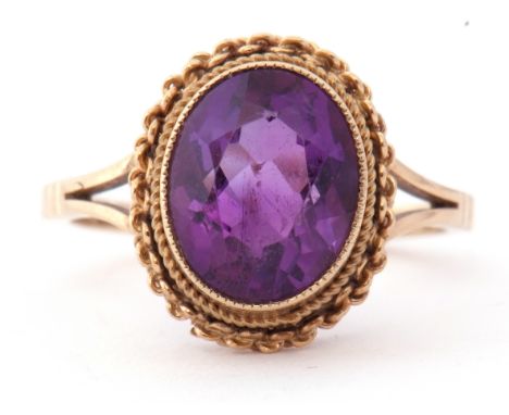 Modern 9ct gold and amethyst ring, the oval faceted amethyst bezel and milliegrain set with a rope twist surround, raised abo